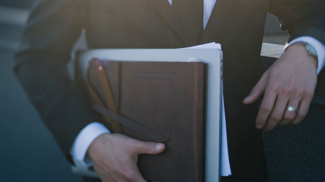 man holding a laptop and a notepad