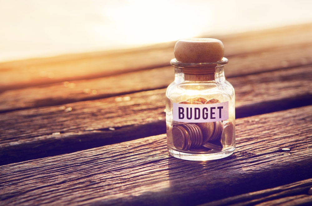 Coin in piggy bank with text budget on paper, on table wood, Light and shadow, business and finance concept, copy space. retro filter effect.