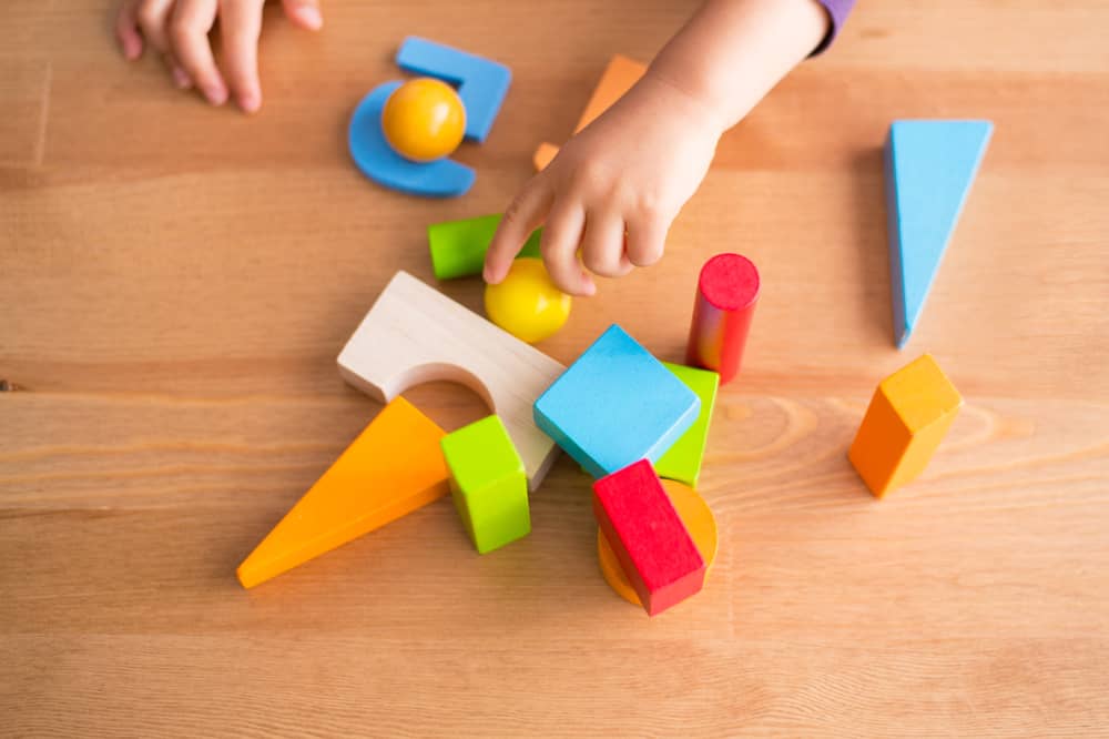 A child plays with colourful wooden shapes.