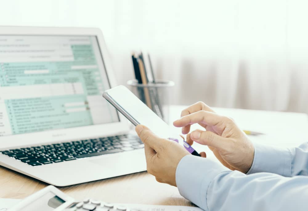 A man works on a large smartphone and laptop.