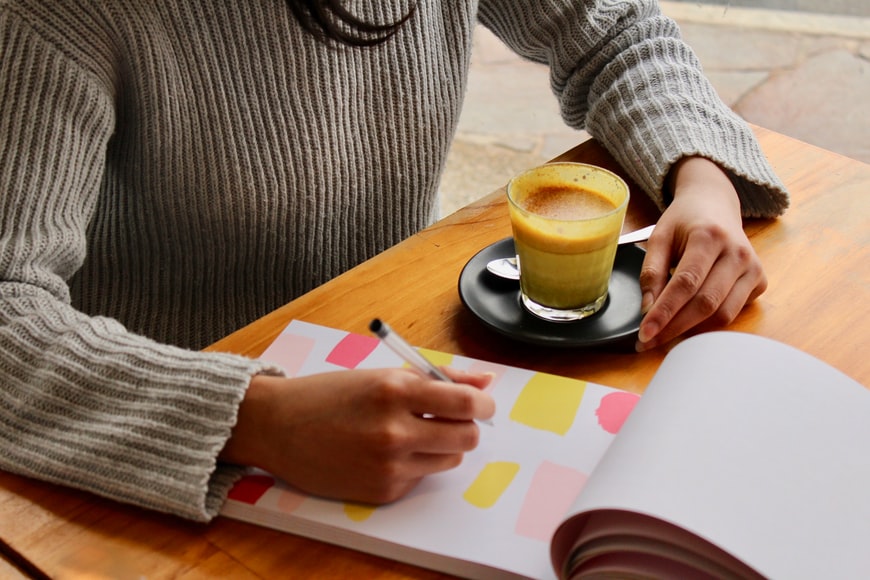 A woman sits with a drink to plan.