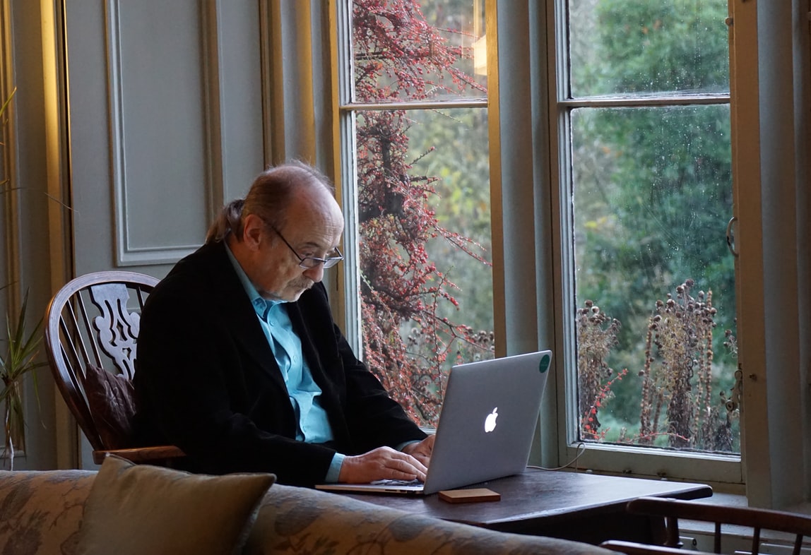 Elderly Gentleman works on macbook.