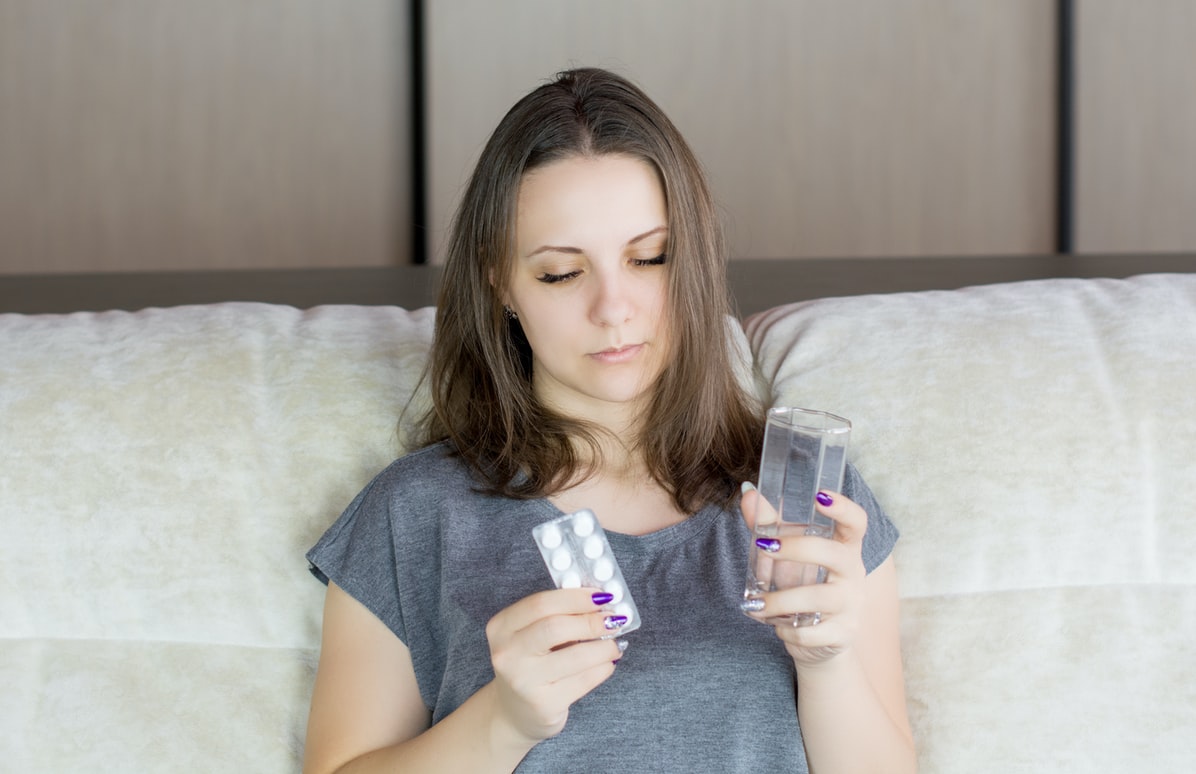 A woman takes tablets with water.