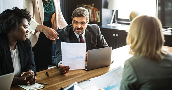 professionals in office, man in suit looking at report