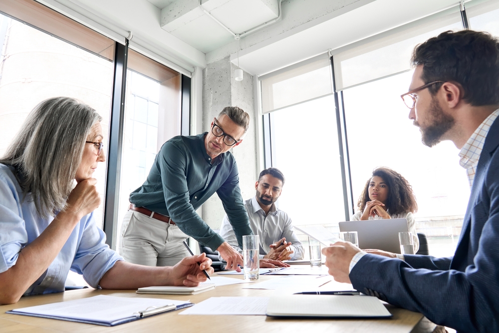 A Group of Five People in Conversation in a Meeting Room