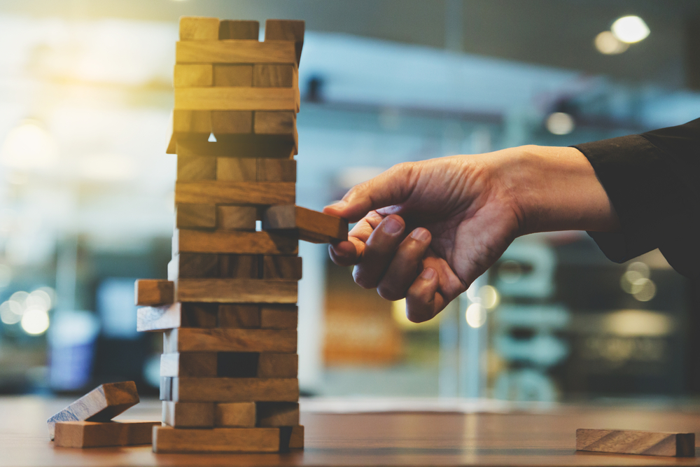 Hand,Of,Businessman,Pulling,Out,Wooden,Block,Risk,Concept