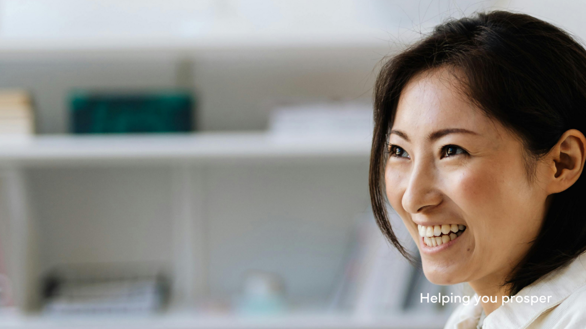 Female in white lab coat in lab setting smiling to someone off camera