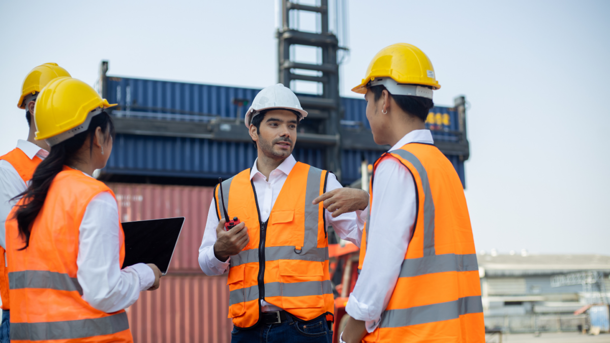 Three young engineers chatting next to a cargo container