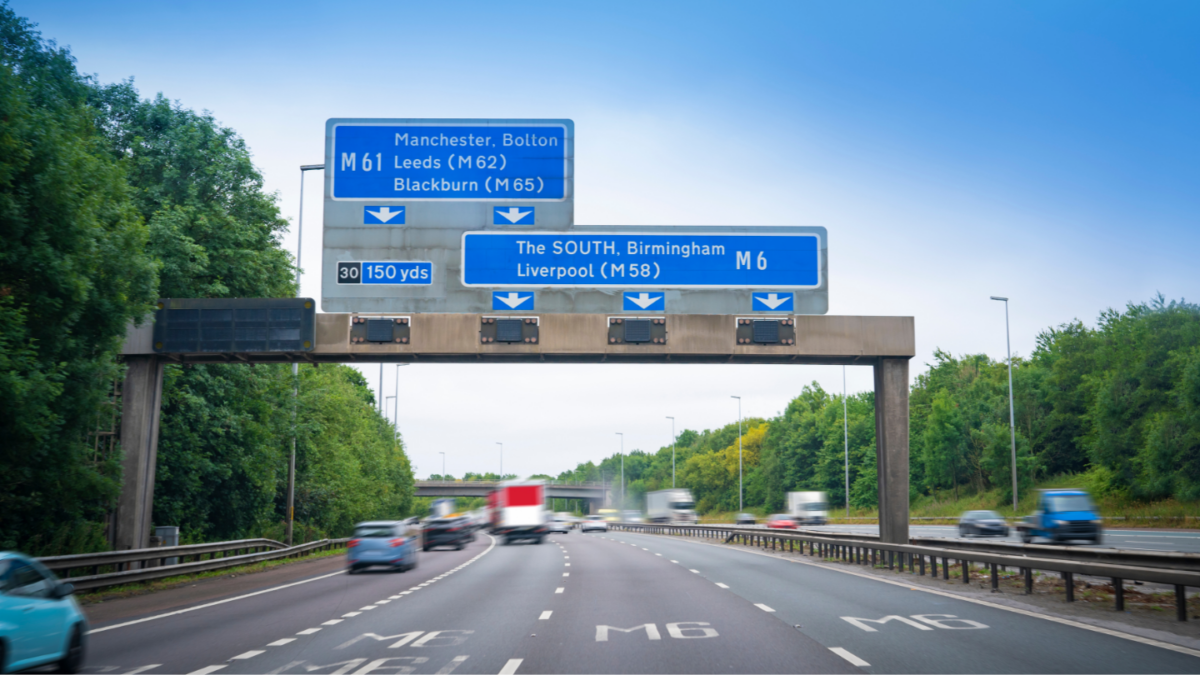 An image of the M6 motorway with overhead gantries mentioning Liverpool and Manchester
