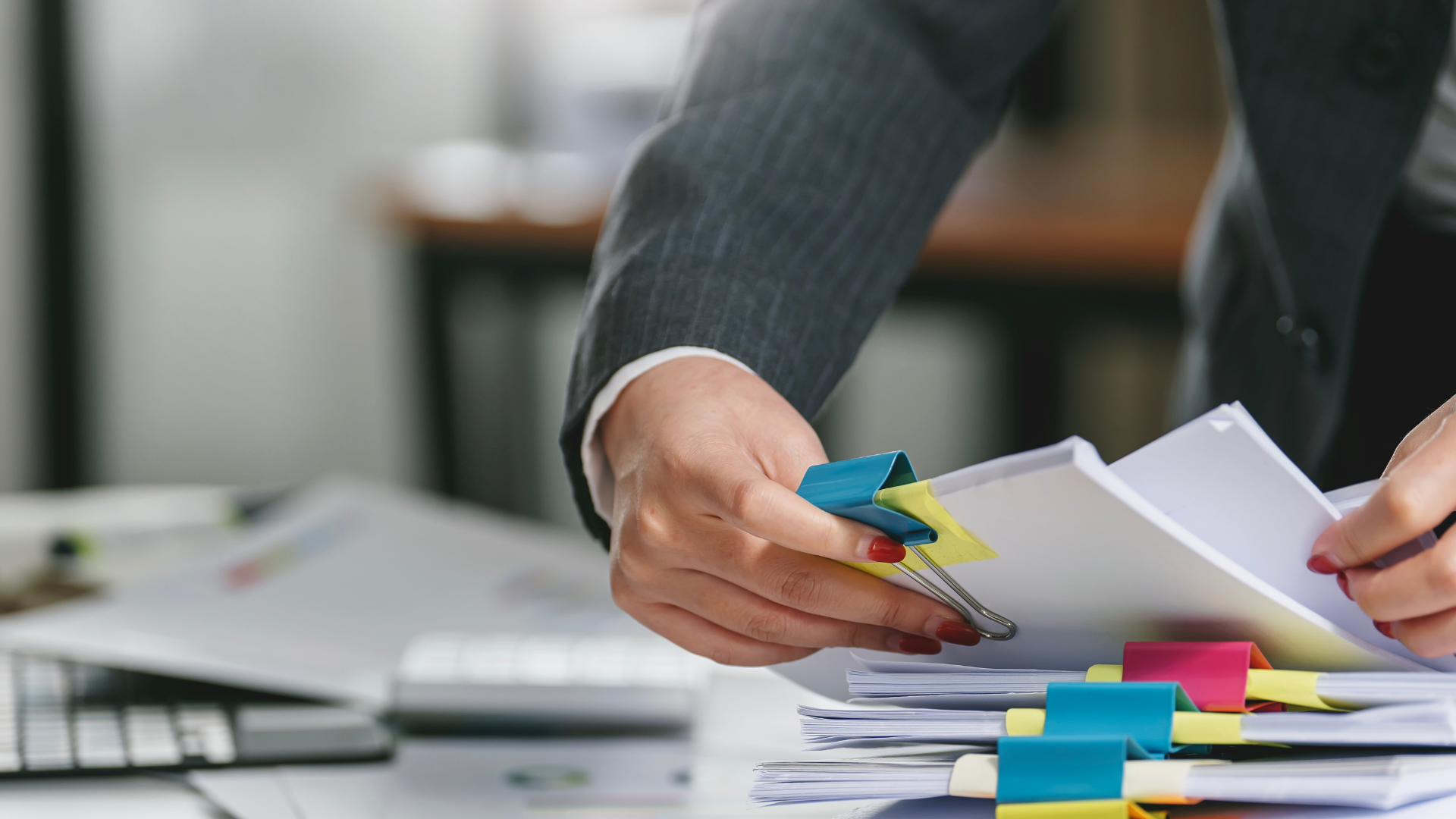 A business person shuffling files with brightly coloured bull dog clips